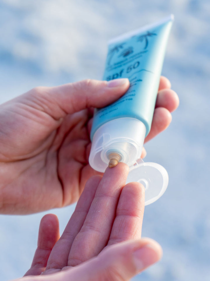 Woman squeezing The Beach Rooster SPF 50 mineral suncreen to her finger 